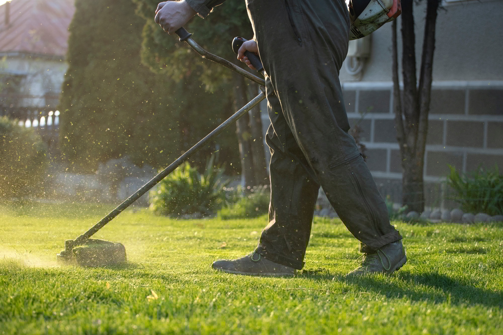 Garden worker with lawn mover. Garden works in spring.